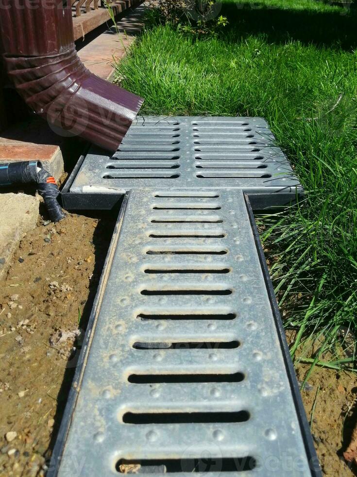 drainage systems. a pipe from the roof and a grate on the ground to drain water. waste water protection photo