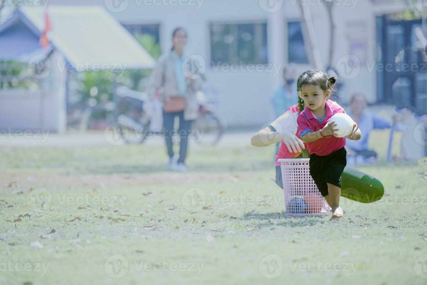 Girl holding a white ball in her hands, running in the park, playing with her children's friends. photo