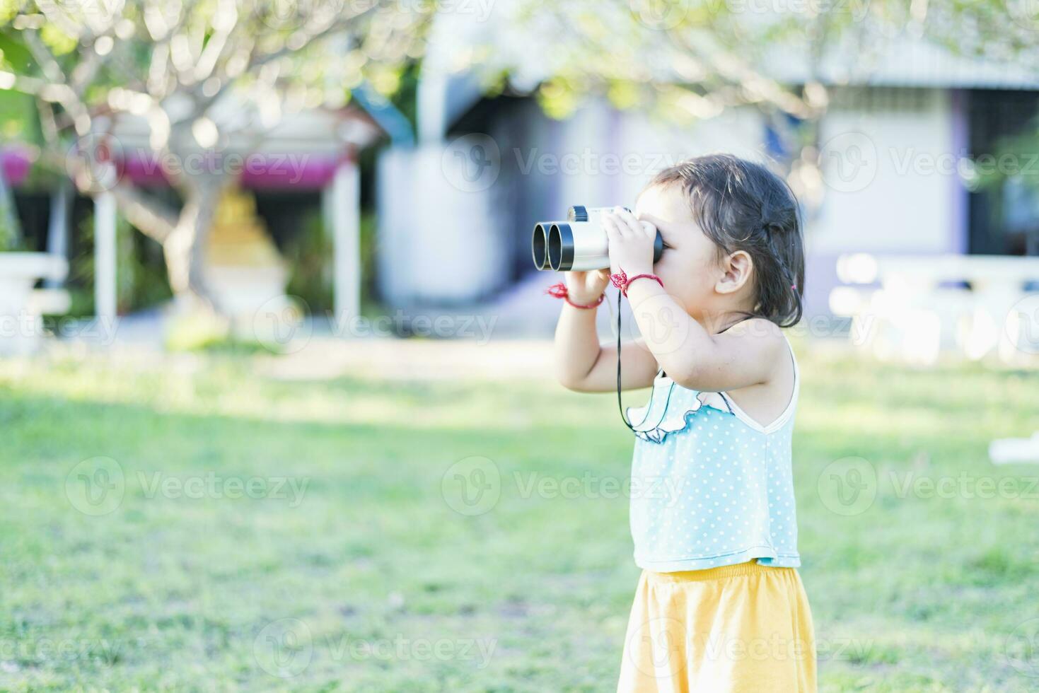 Beautiful young woman looks through binoculars at the national park on a sunny day. photo