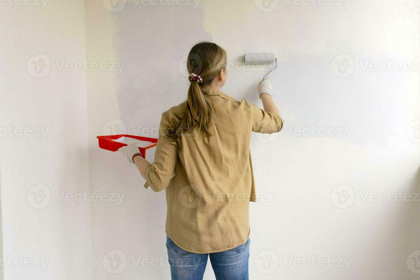 Womens hands using paint roller while working indoors photo