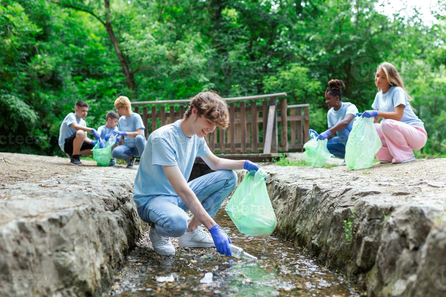 Volunteer young man collecting plastic rubbish on coast of the river. Cleaning environment concept photo