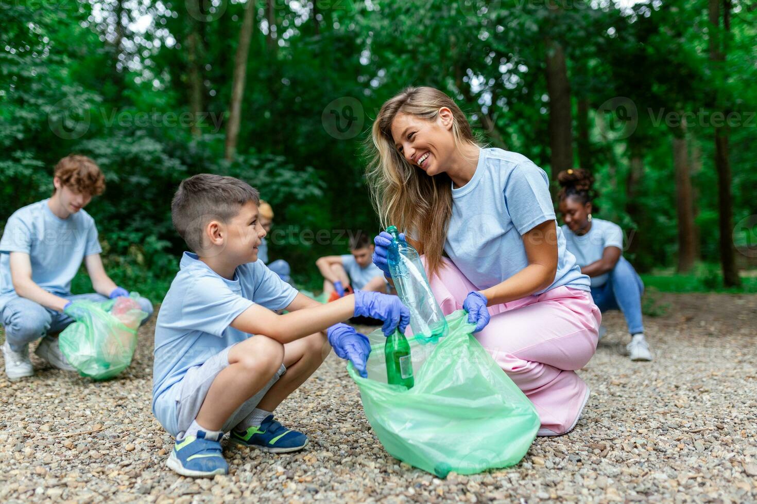 Mother and kids are picking up the garbage to clean up the forest photo
