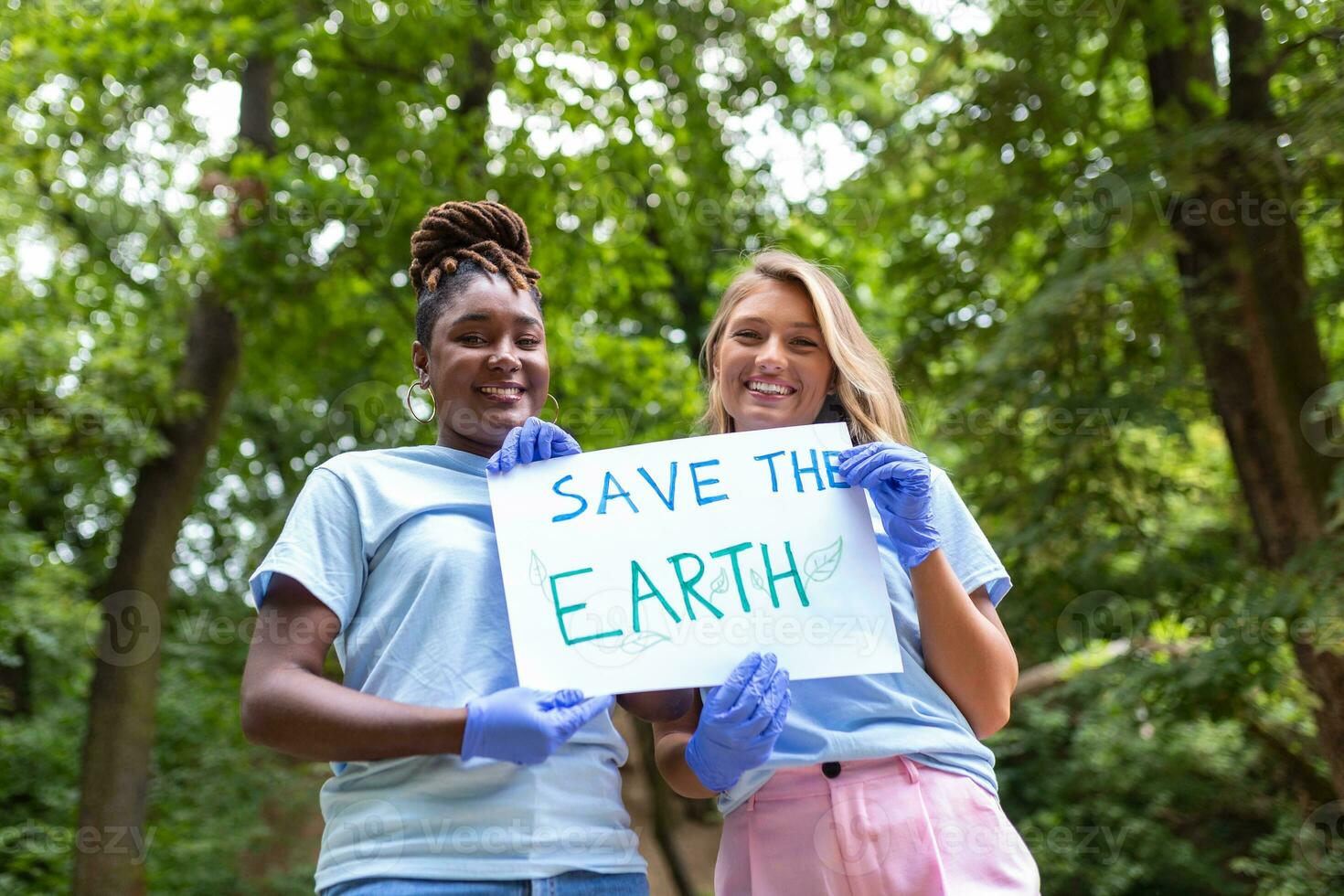 Two volunteers of different races hold a paper and show how important it is to take care of the environment. Volunteering concept. photo