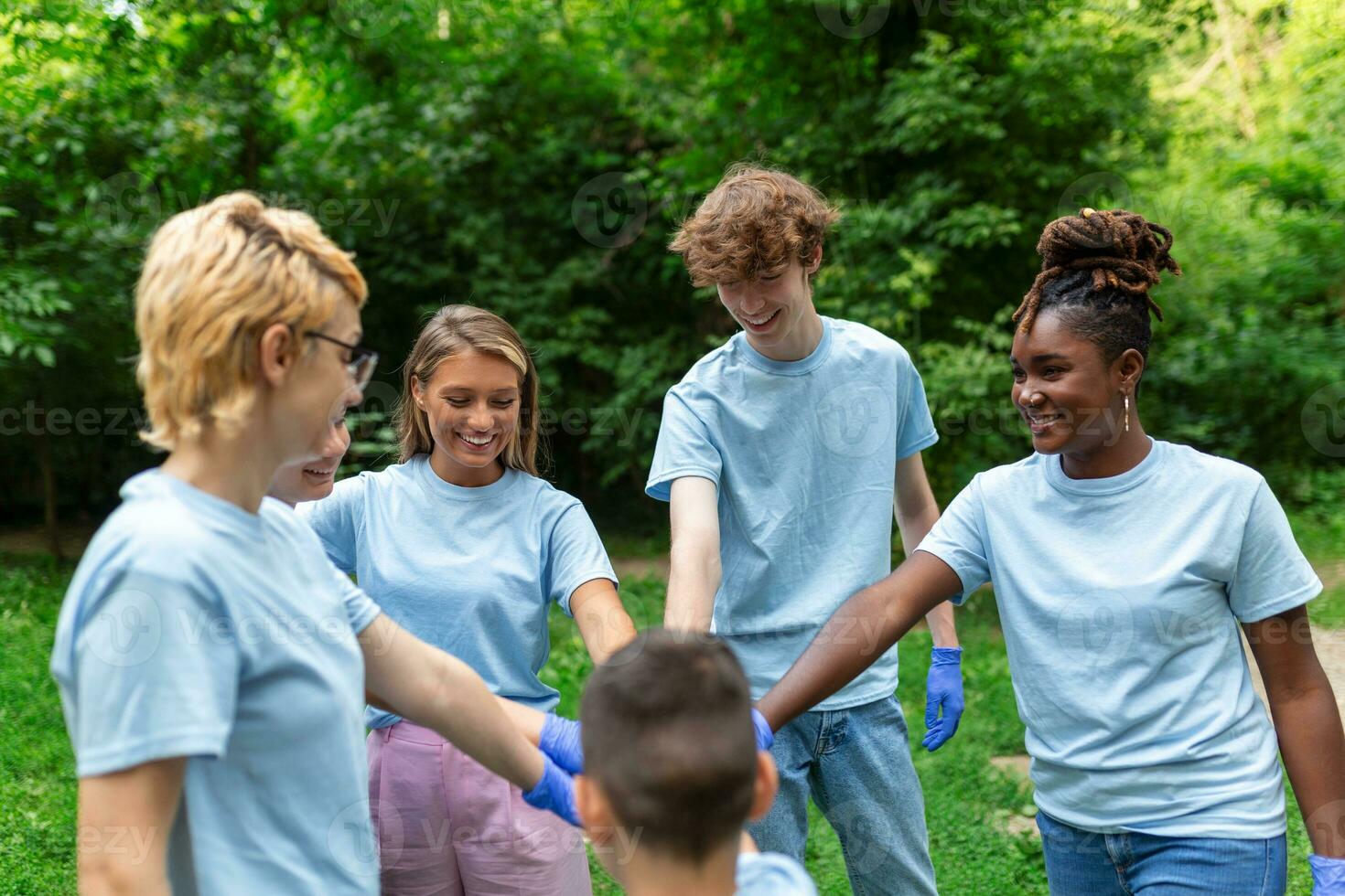 Group of multiracial volontaire young people building team outdoor in park, join hands together. photo