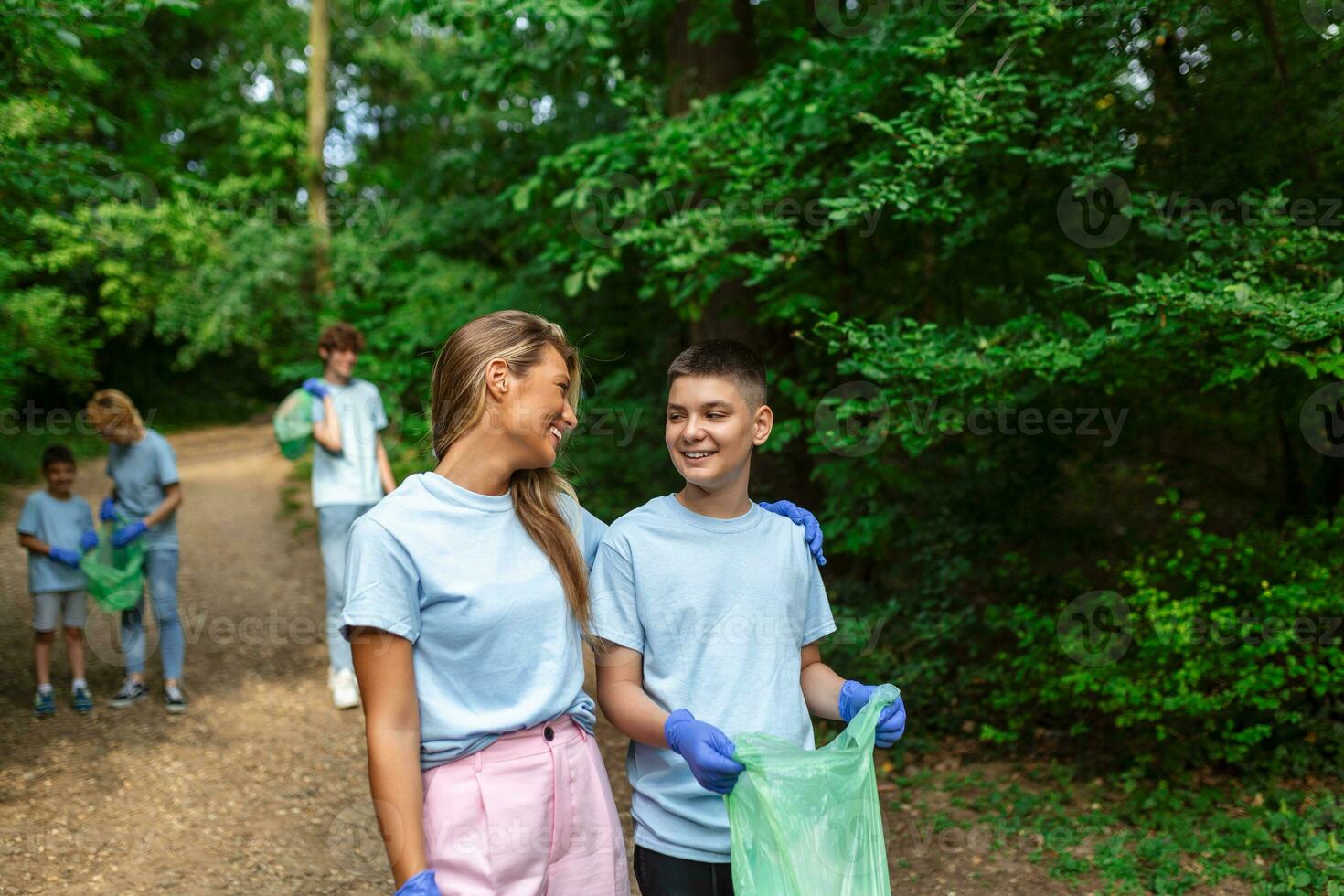 Group of volunteers cleaning up forest from waste, community service concept photo