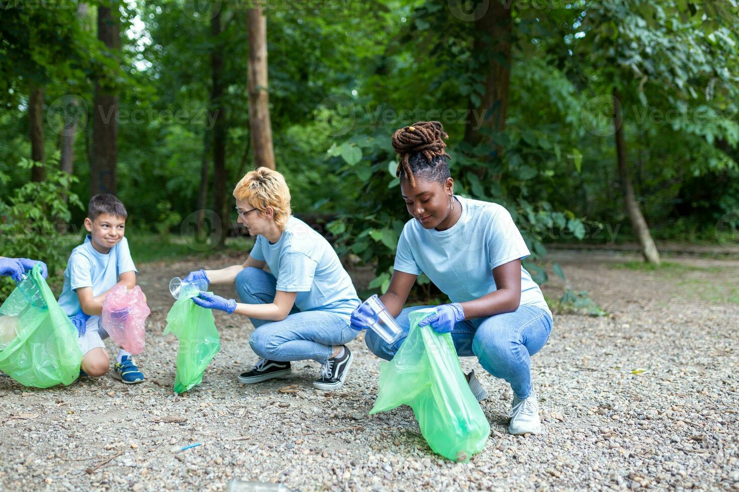 A group of people are cleaning together in a public park, protecting the environment. Woman in the foreground with a garbage bag in her hand cleans the park photo