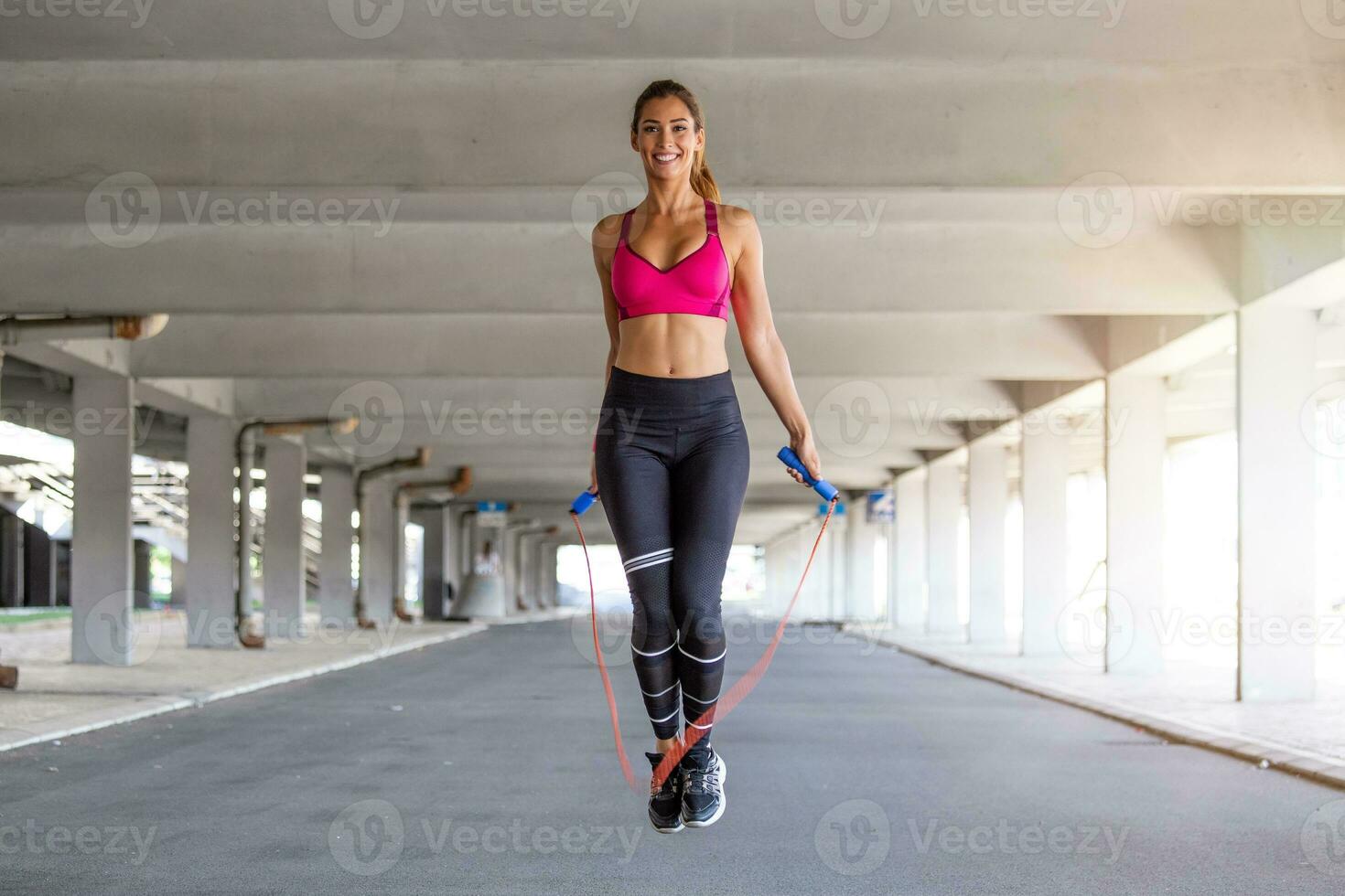 Fitness woman skipping with a jump rope outdoors. Female doing fitness training in morning. Athletic Beautiful Woman Exercises with Jump Skipping Rope. photo