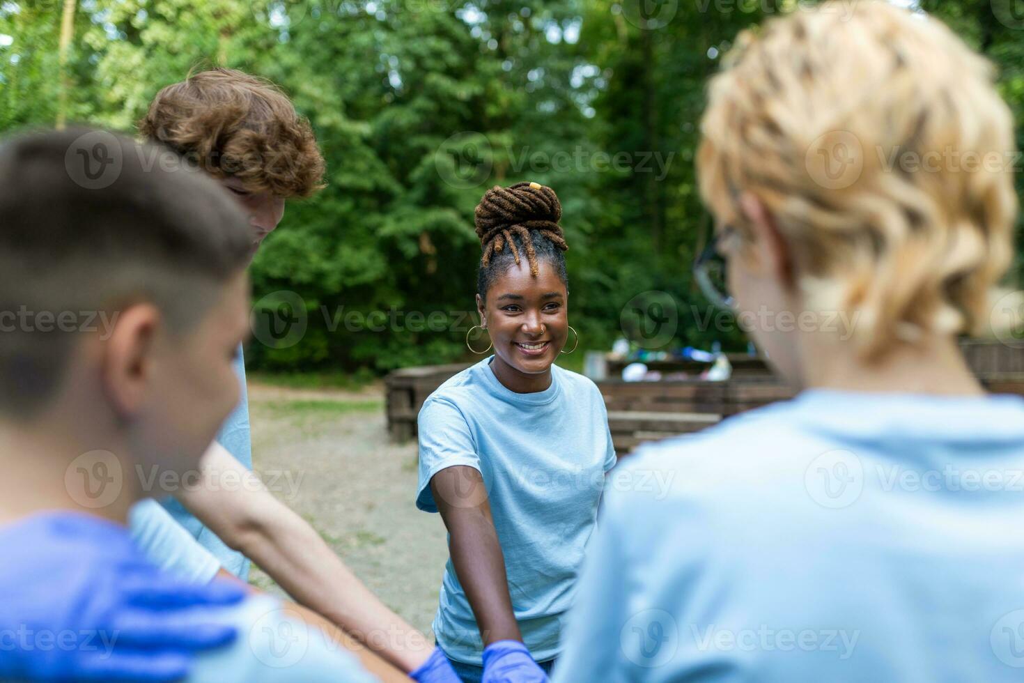 retrato de voluntarios plegable su brazos. ambientalistas son en un público parque. ellos son en azul camisetas el concepto de amistad y Ayudar foto