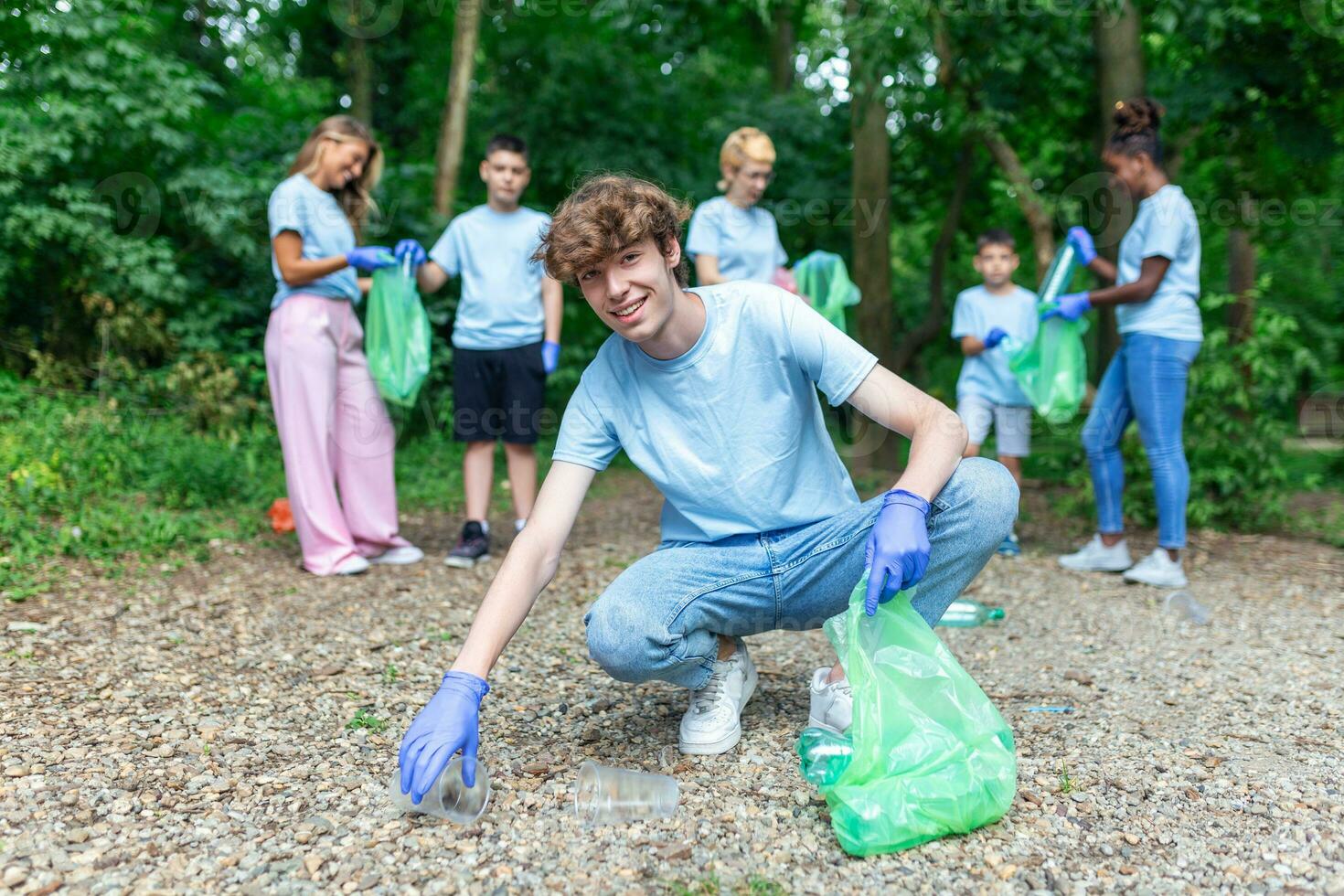 volunteering, charity, cleaning, people and ecology concept - group of happy volunteers with garbage bags cleaning area in park photo