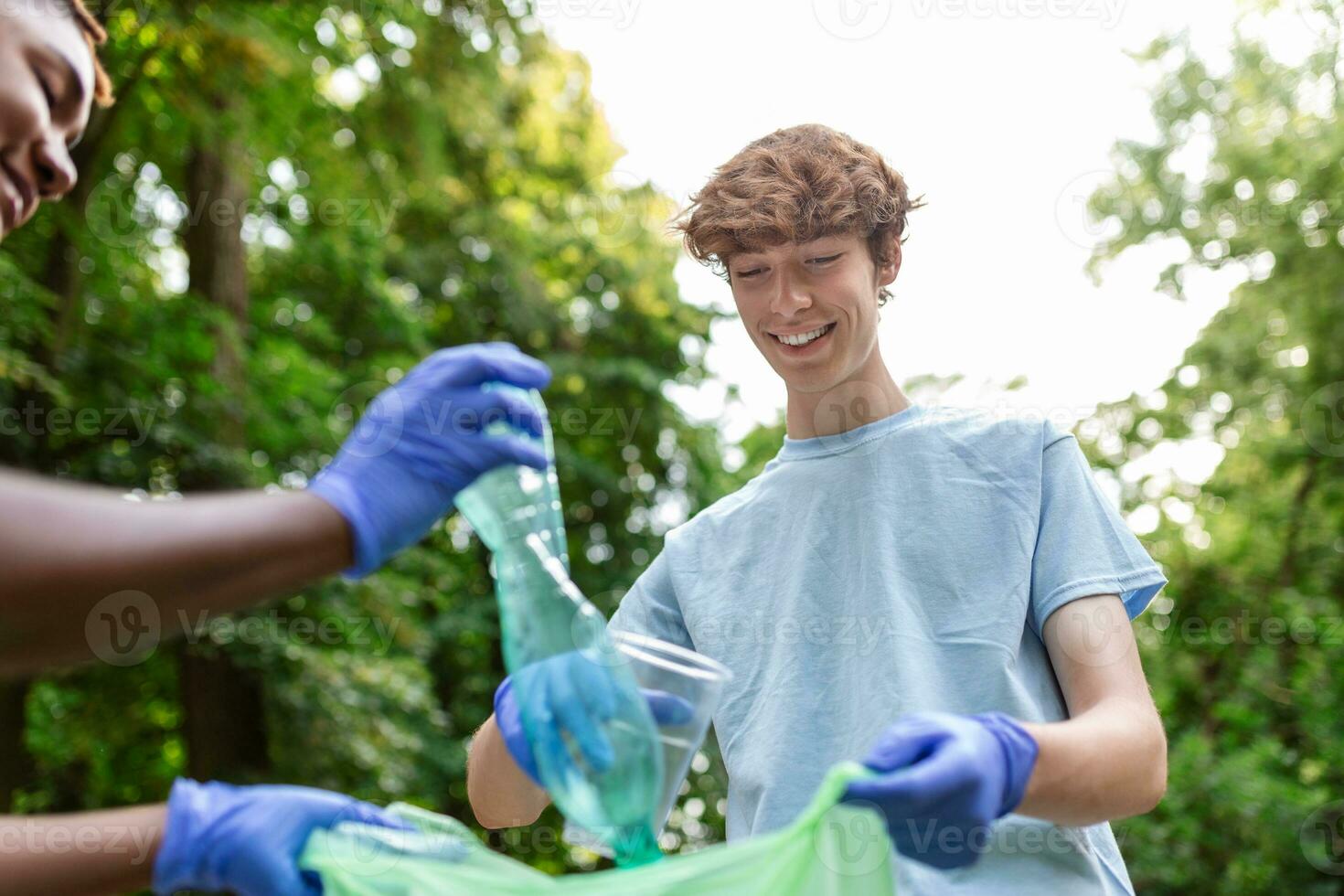 Young responsible people doing community charity work in the park. Group of people, cleaning together in public park, saving the environment. photo