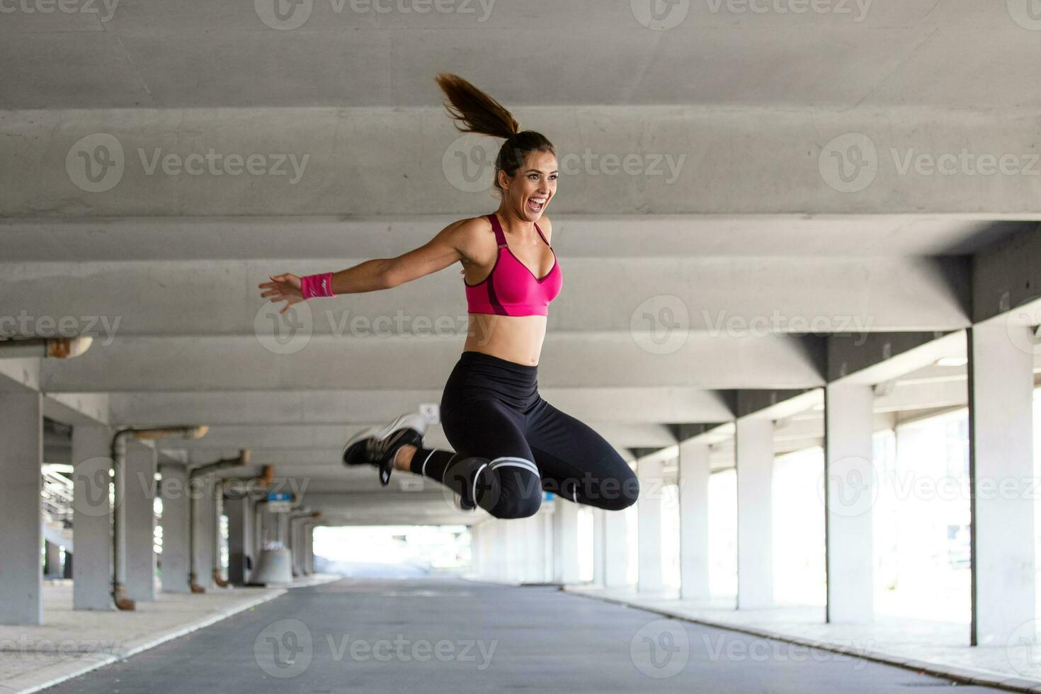 aptitud mujer saltando al aire libre en urbano ambiente. activo mujer siendo lleno de energía, saltos alto en aire, prepara para deporte competiciones . gimnasia concepto foto