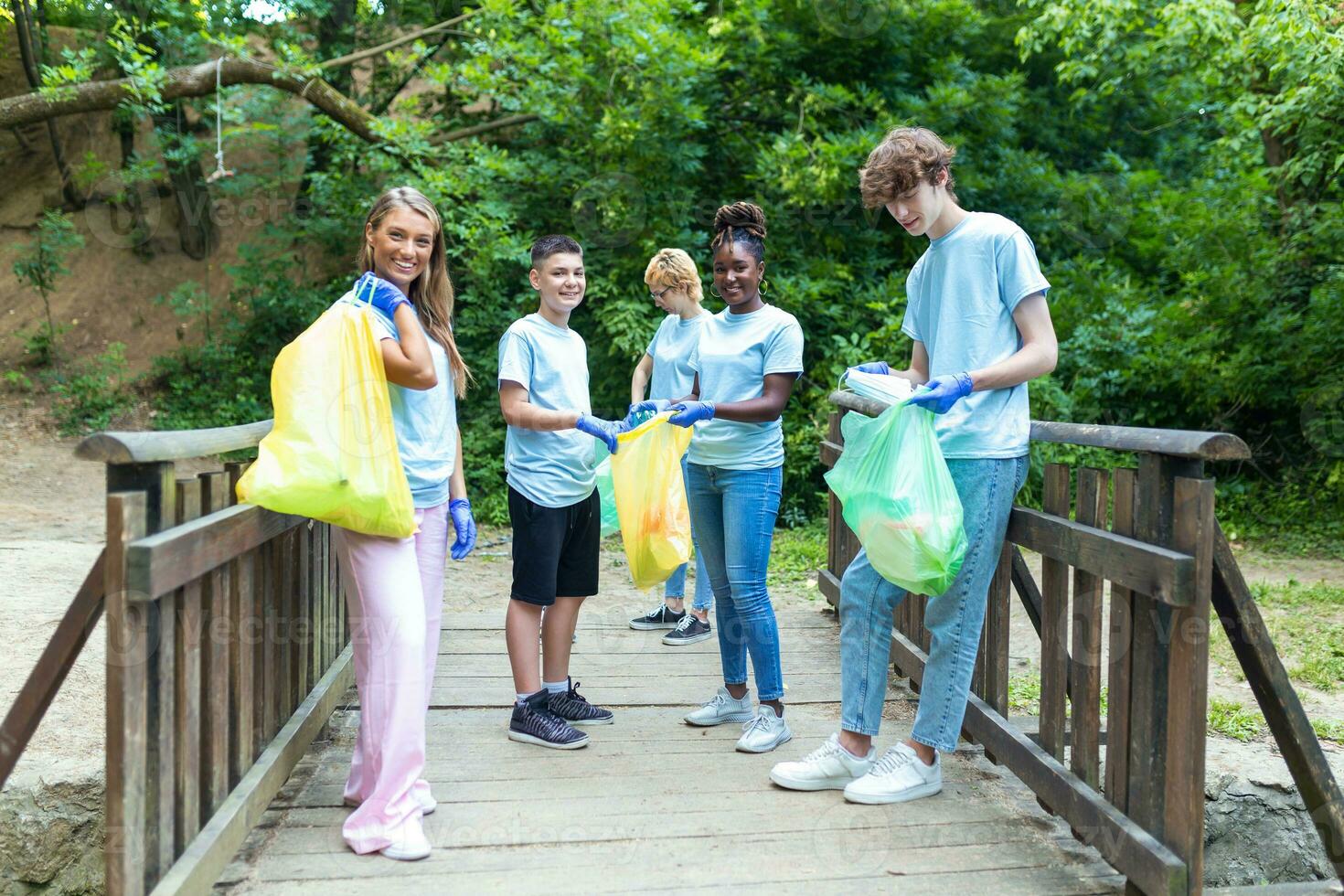 Standing in a natural parkland and holding full garbage bags, volunteers are standing looking at the camera, showing the results of their environmental clean-up photo