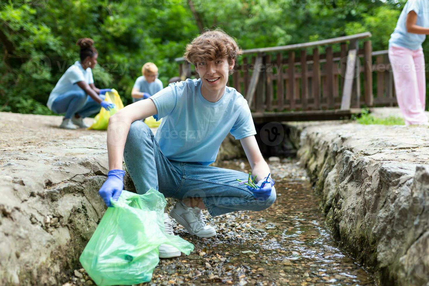 Man handpicking gathering up garbage plastic straws garbage from the river at the park. World environment day.Environment concept. photo