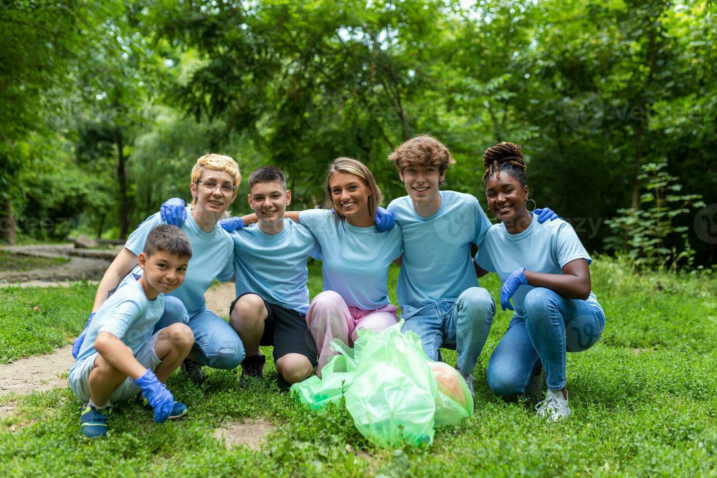 Standing in a natural parkland and holding full garbage bags, volunteers are standing looking at the camera, showing the results of their environmental clean-up photo