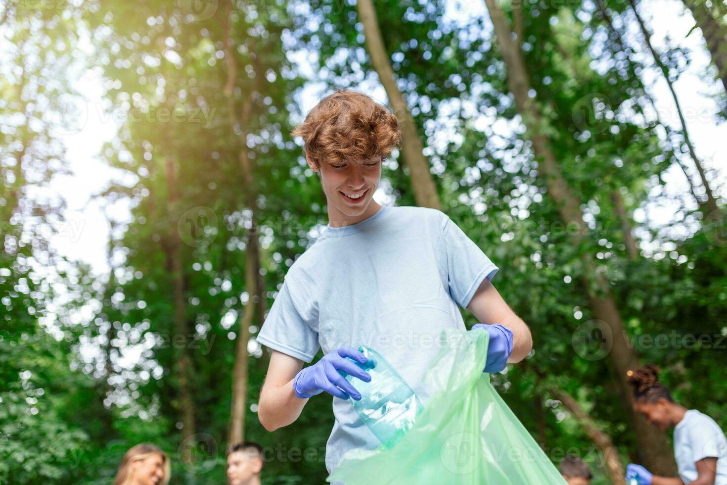 Group of volunteers cleaning up forest from waste, community service concept photo