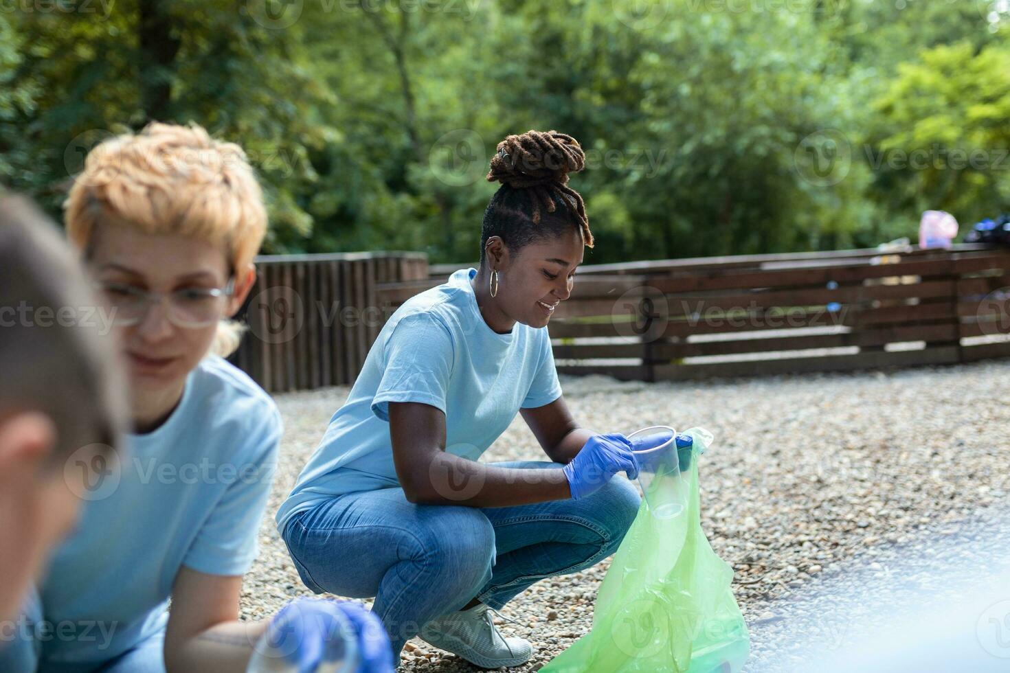 Group of volunteers cleaning up forest from waste, community service concept photo