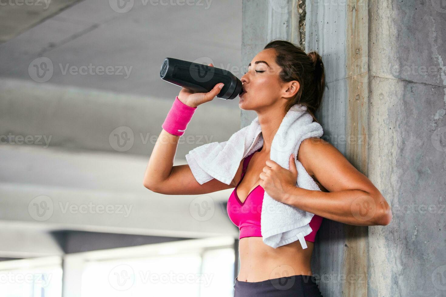 Shot of beautiful female runner standing outdoors holding water