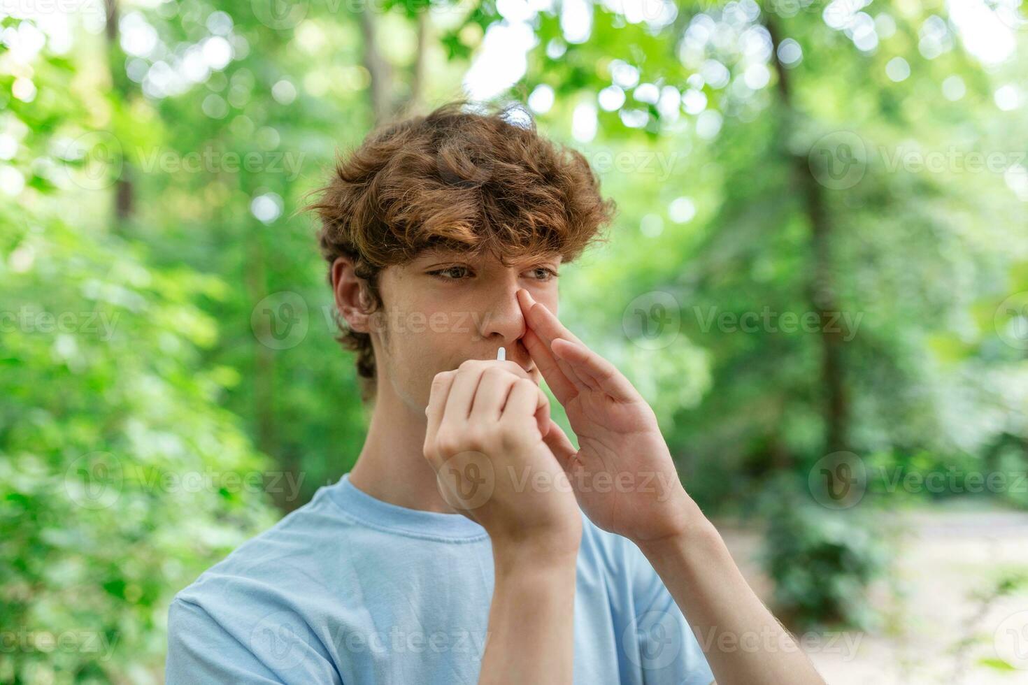 Young man is Using Nasal Spray Due to the Problems with Nose and Breathing in the Public Park. photo
