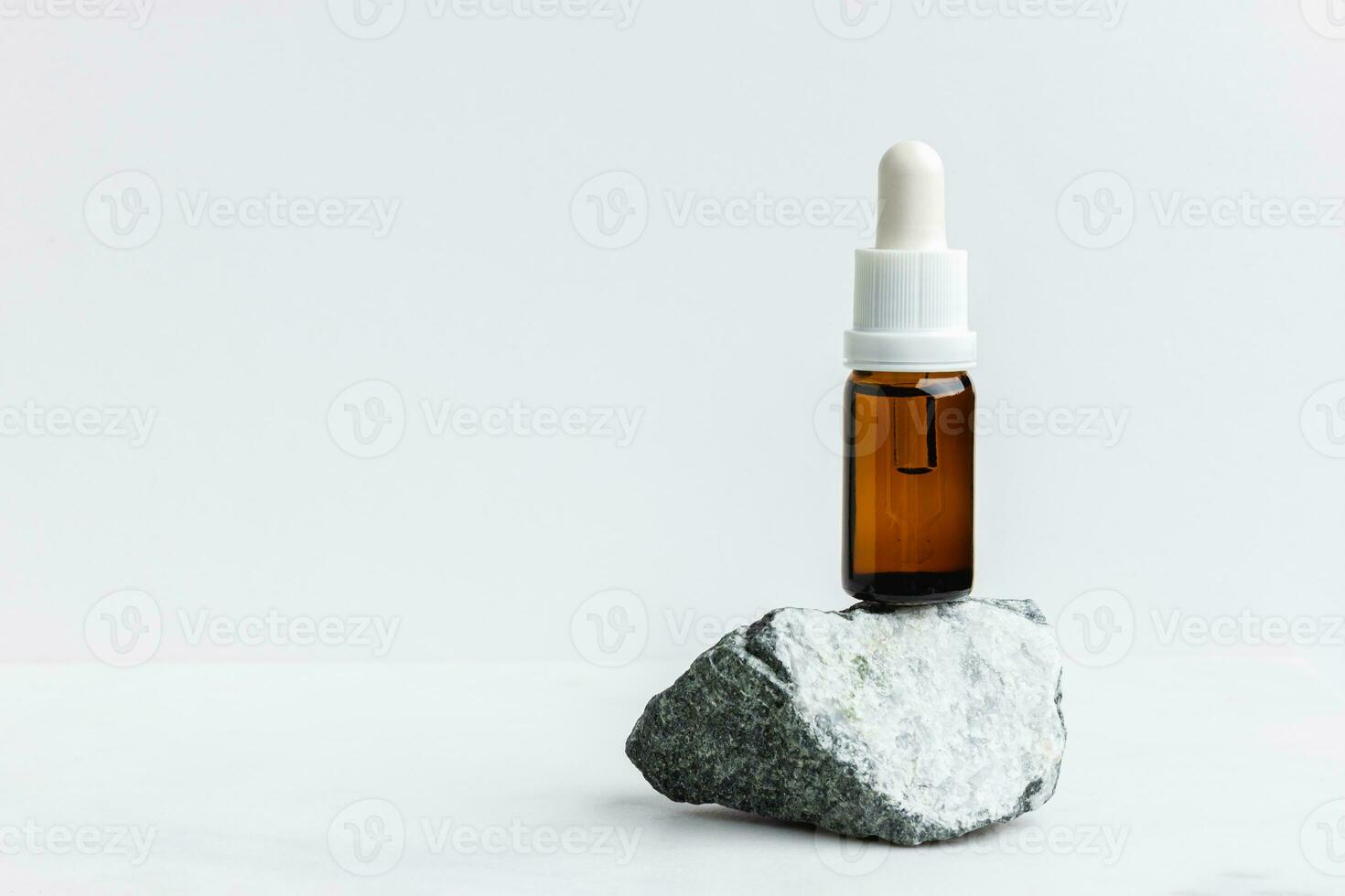 Serum in the brown bottle for face on white marble. photo