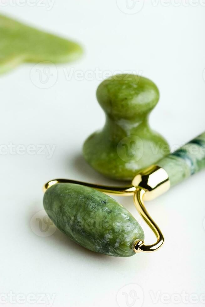 verde jade rodillo masajeadores para cara en blanco mármol. foto