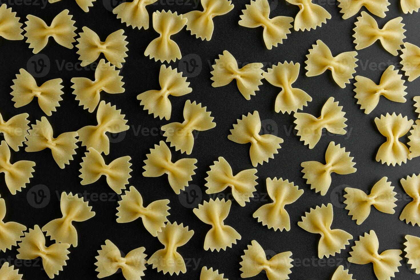 Raw pasta farfalle pattern on black background. photo