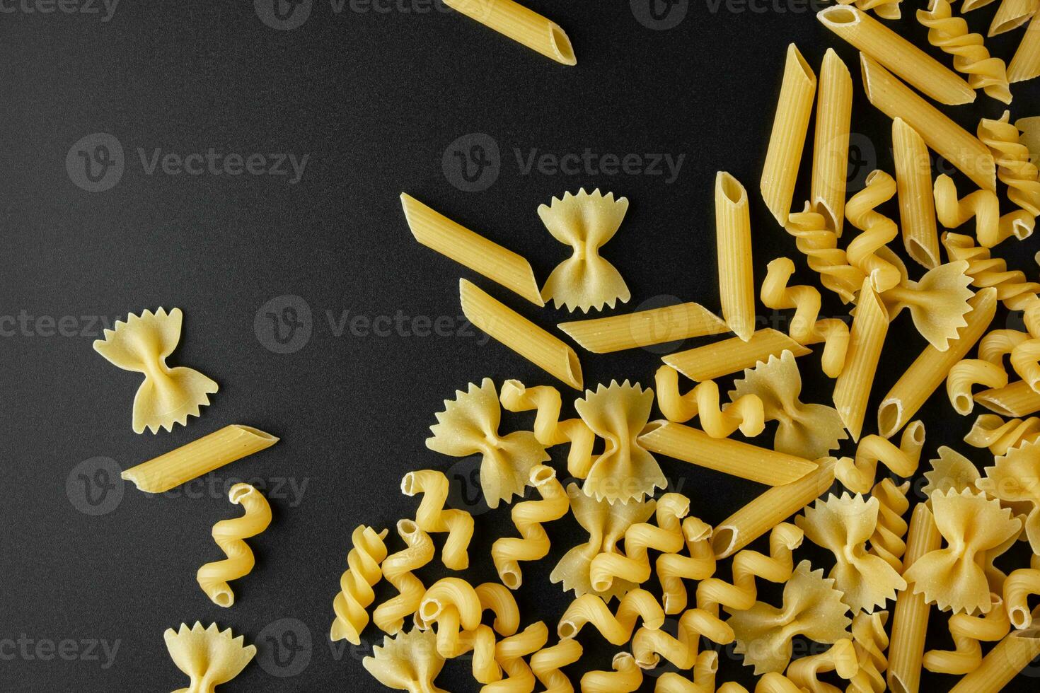 Different kinds of raw pasta with copy space on black background. photo