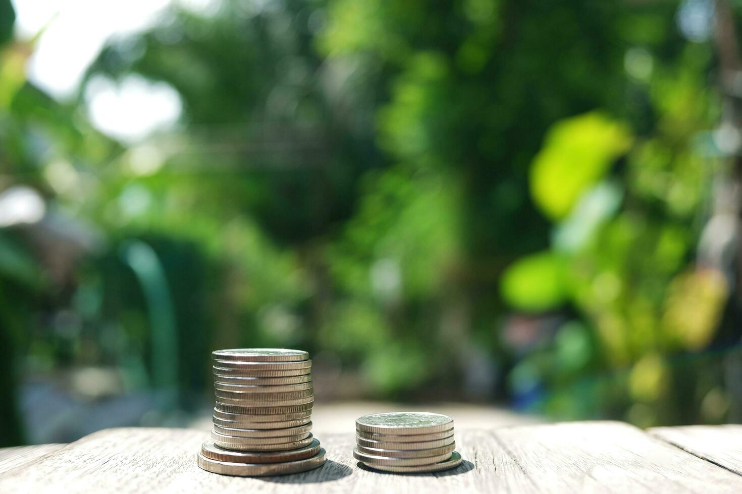 Money coins on wooden floor in green natural bokeh background for Saving and growing in success economy and bussiness life concept. photo