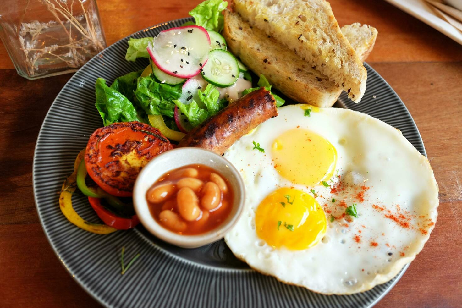 Delicious fried egg, Smoked sausage Butter on Bread Toast with with sauce and vegetable on black dish is homemade breakfast. photo
