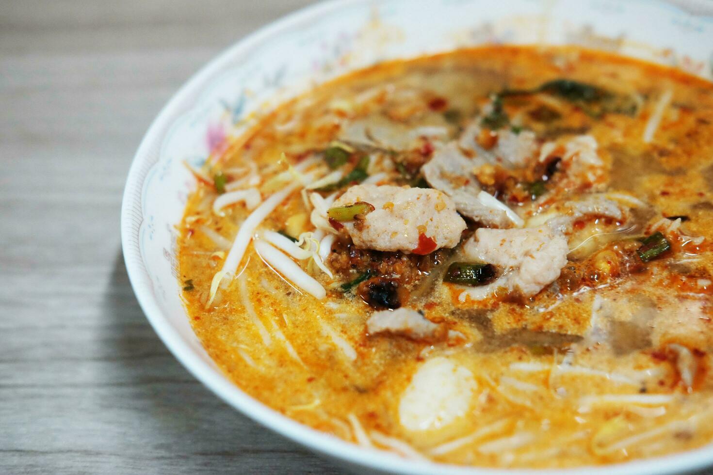 Thai food Spicy TOM YAM pork noodle soup with lemongrass, chilly pasted and lime juice Ingredients on white bowl. photo