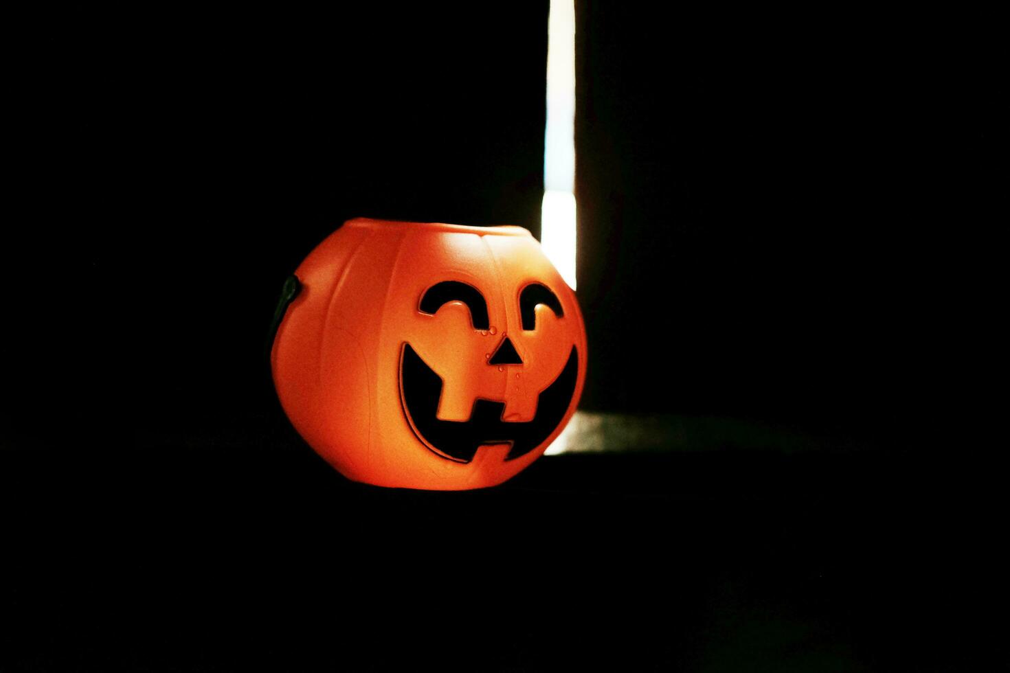 Smiling Halloween pumpkin head on black clothes in natural shadow and sunlight. Halloween holiday concept. photo