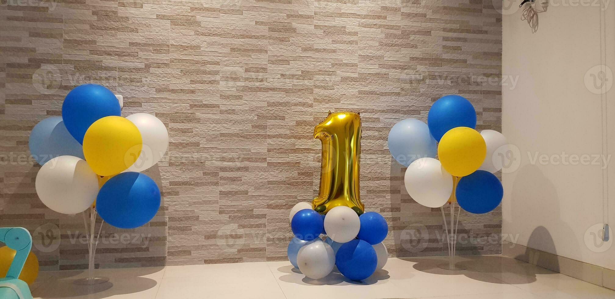 Simple first birthday boy decoration with number one balloon in gold color and balloons in yellow, photo