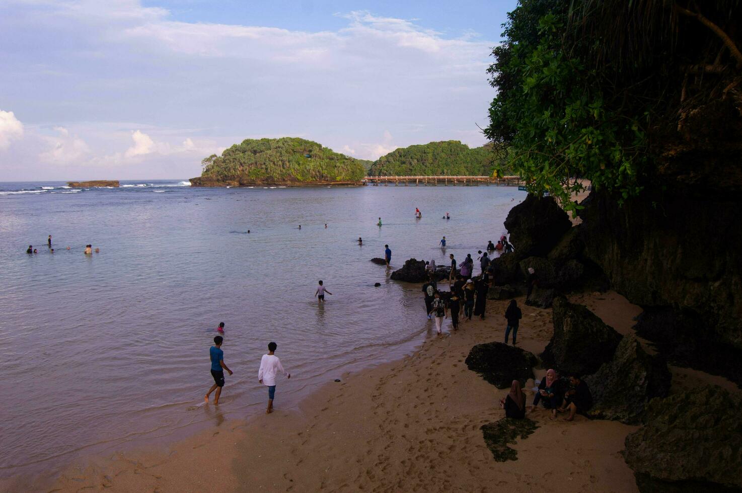 Balekambang beach view with lots of tourists playing in the sand photo