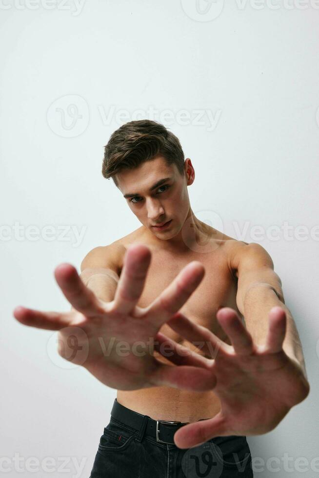 A man with a naked torso gestures with his hands in front of his face cropped view photo