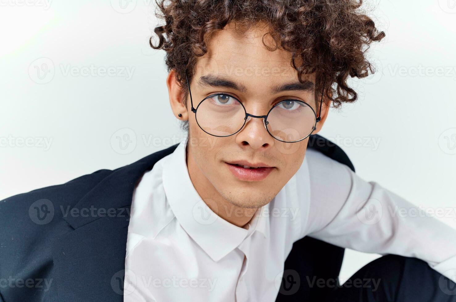 de cerca retrato de hermoso chico con Rizado pelo vistiendo lentes y en un clásico traje foto