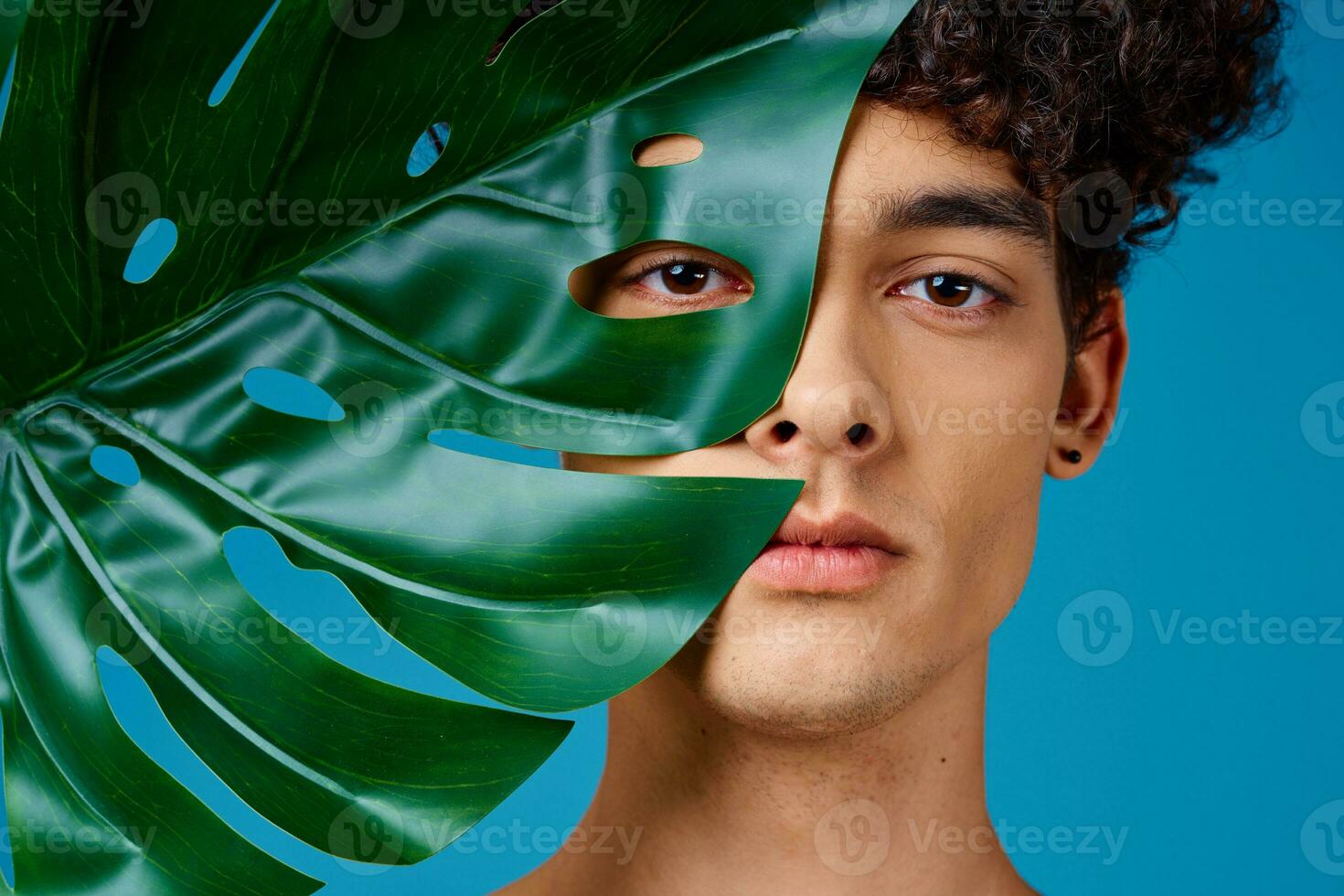 Cheerful guy with curly hair green leaf close-up clean skin photo