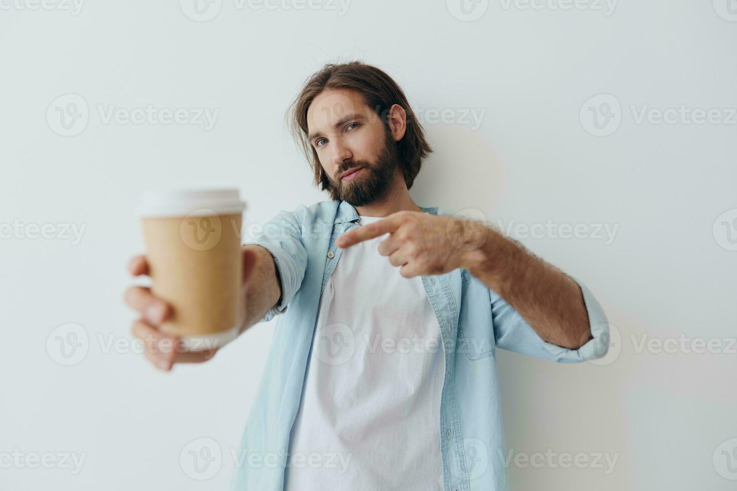 Freelance Millennial man with a beard drinking coffee from a recycled cup in stylish hipster clothes white T-shirt blue jeans and shirt on a white background photo