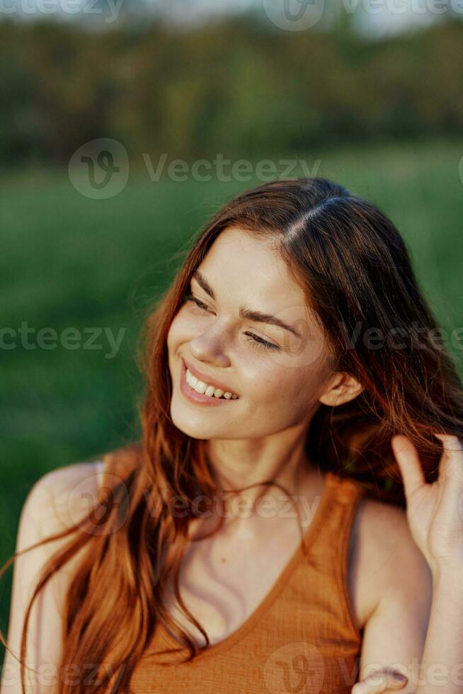 A beautiful redheaded woman laughs and smiles with her teeth in the bright sunset sunlight. The concept of healthy living and good nutrition photo