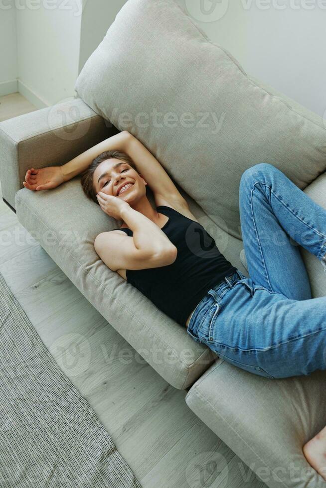 joven mujer con corto Corte de pelo pelo teniendo divertido a hogar en el sofá sonrisa y felicidad, vacaciones a hogar, natural posando sin filtros, gratis Copiar espacio foto