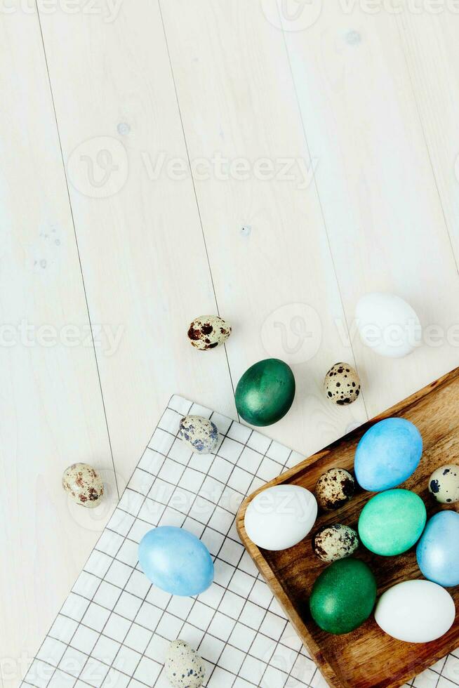 Easter eggs of different colors lie on a wooden table Copy Space and a checkered napkin photo