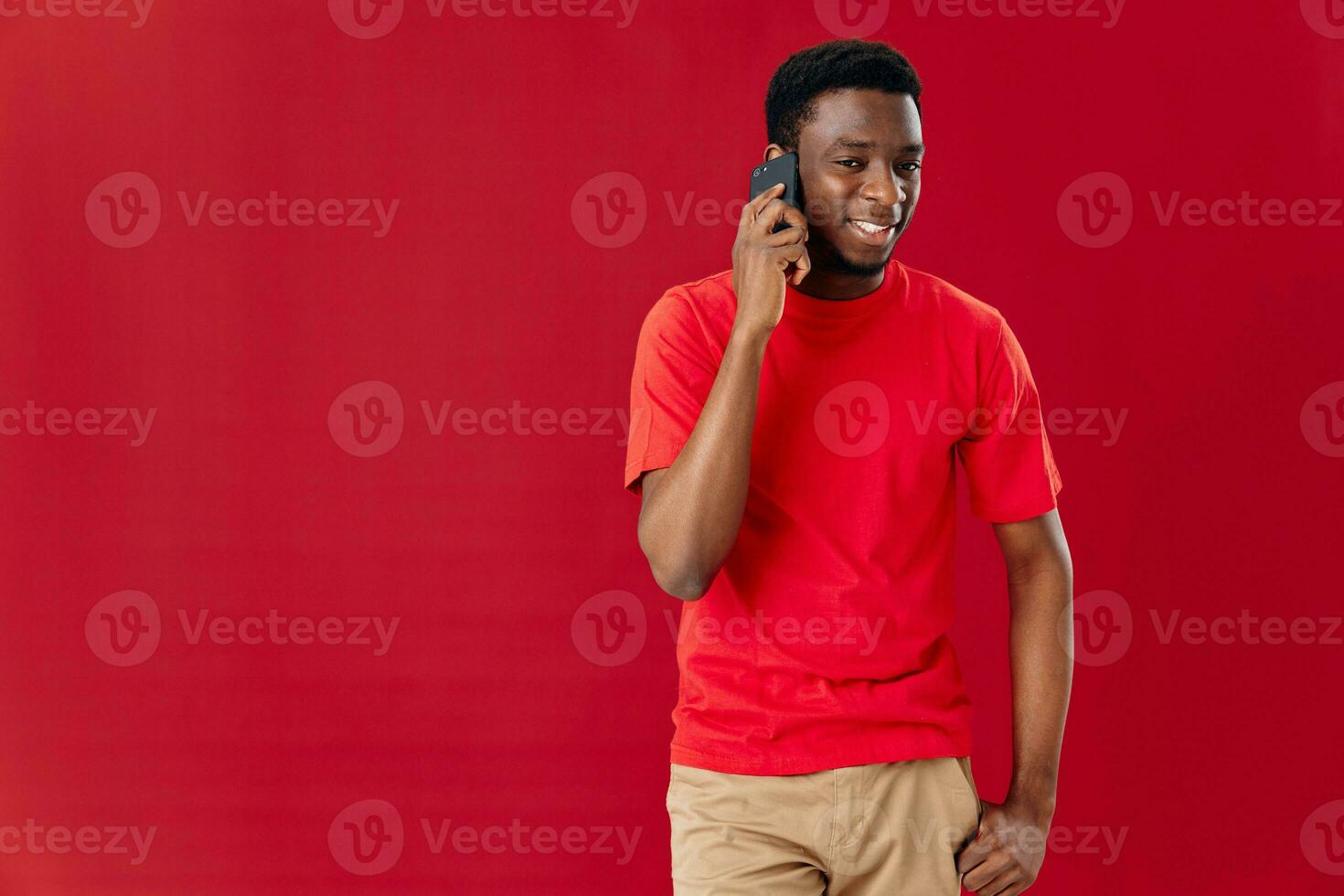 African American in a red t-shirt with a phone in his hands communicates photo