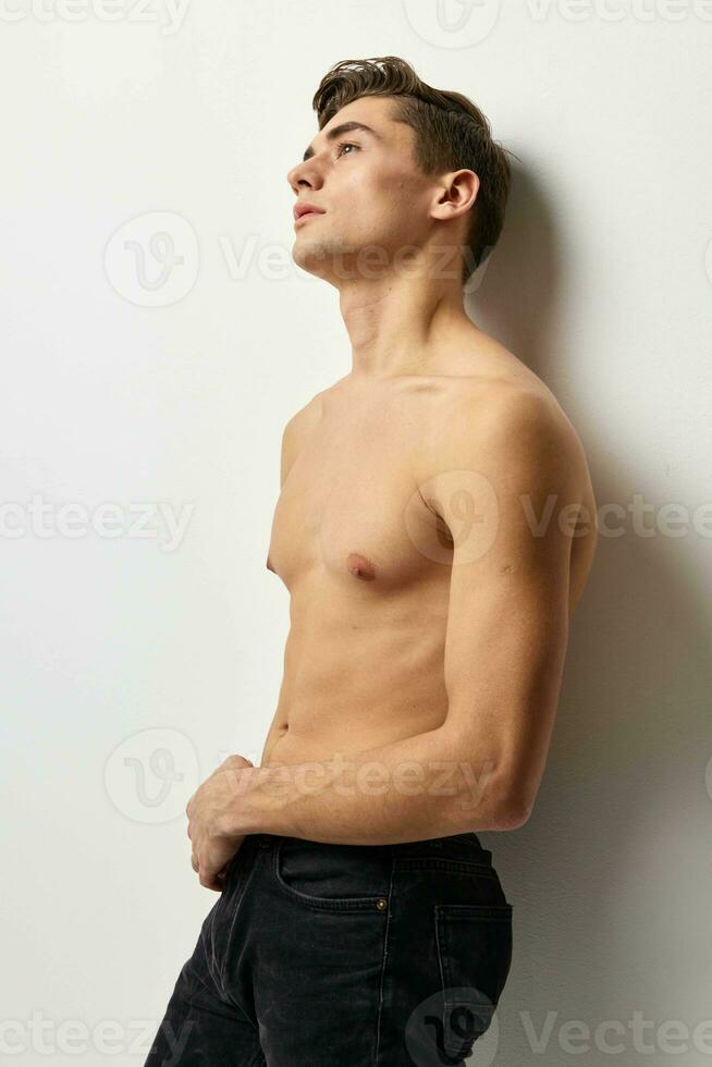 joven hombre con un desnudo torso mirando arriba posando auto confianza ligero antecedentes foto