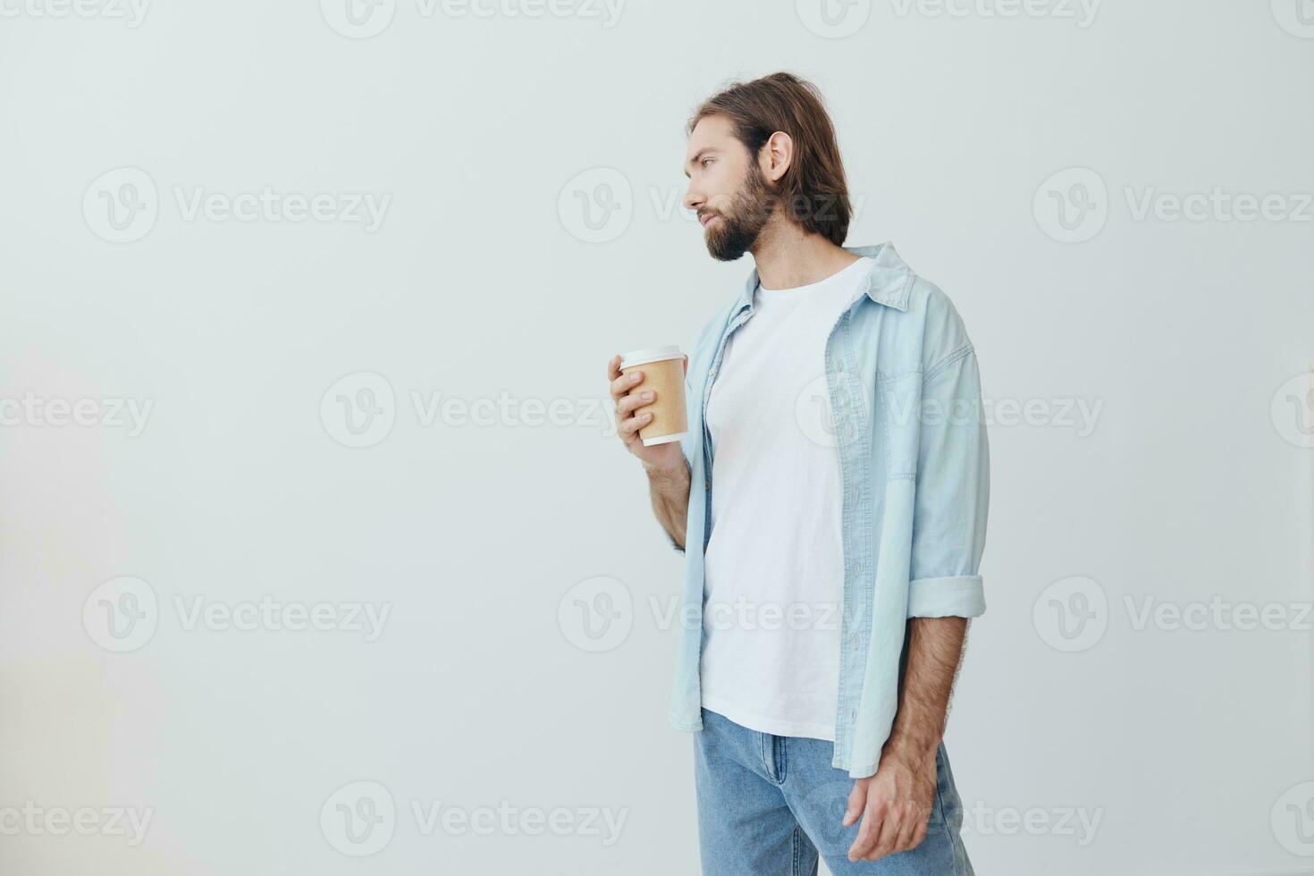 Lanza libre milenario hombre con barba Bebiendo café desde un cangrejo taza en elegante hipster ropa en un blanco antecedentes foto