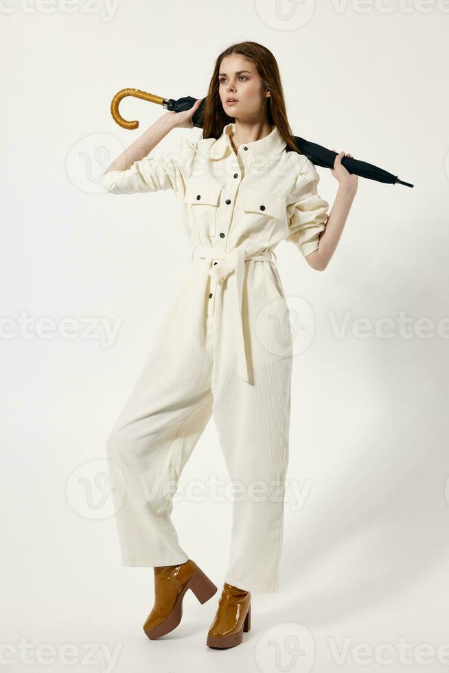 fashionable woman in white jumpsuit umbrella in hands studio full growth photo