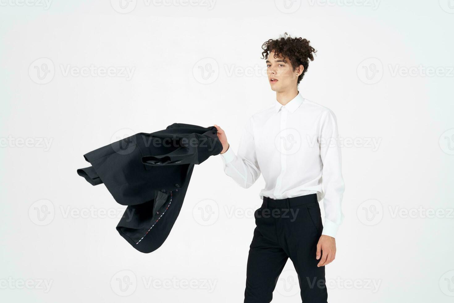 young man with curly hair and in a classic suit holds a jacket in his hand fashion style photography studio model photo