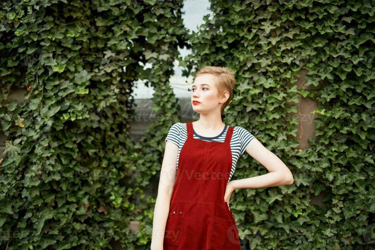 pretty woman with short hair outdoors on a background of bushes photo