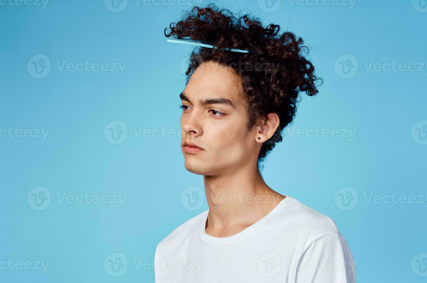man with comb stuck in curly hair close-up portrait and white t-shirt photo