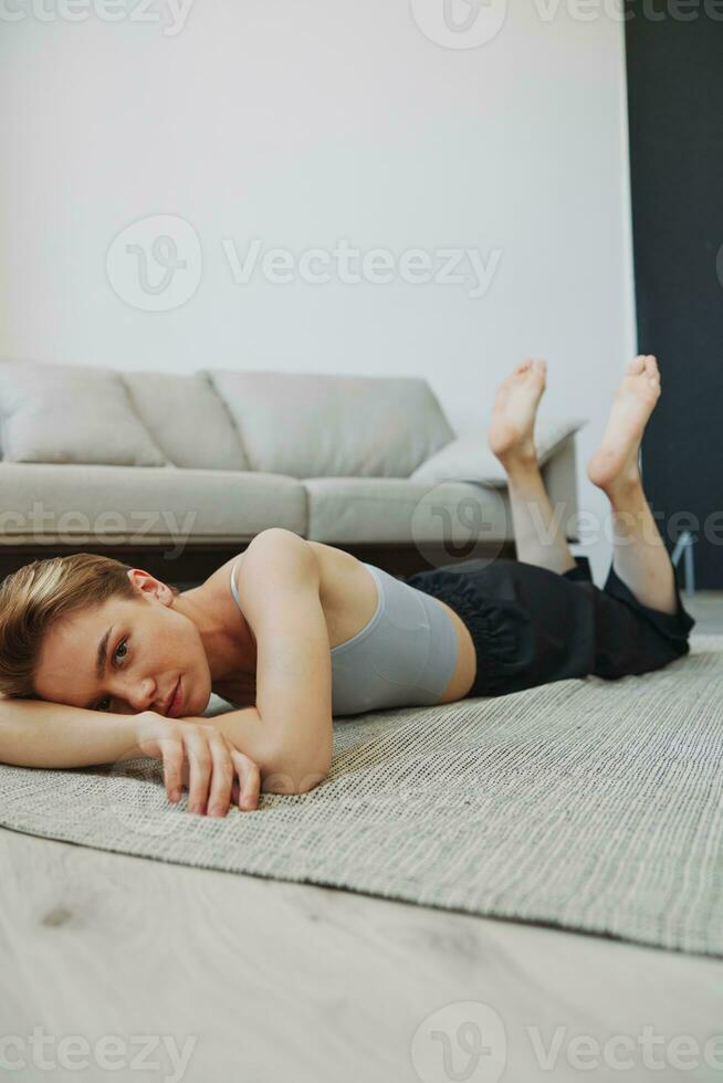 Teenage girl lying on the floor at home smiling in home clothes with a short haircut, lifestyle without filters, free copy space photo