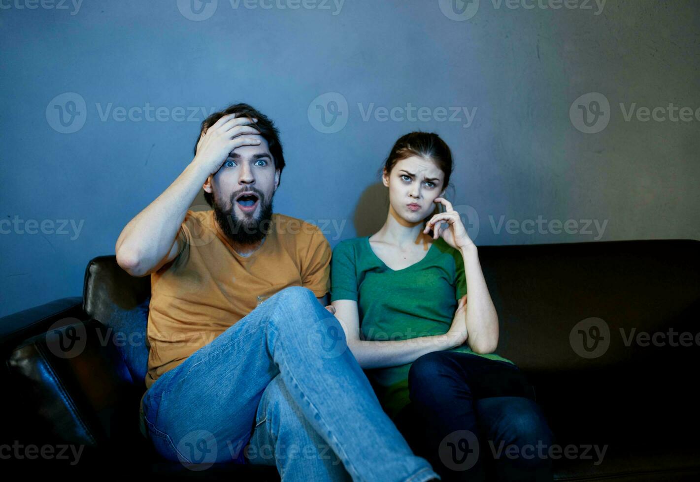 alegre hombre y emocional mujer en un negro sofá adentro en el noche acecho televisión foto