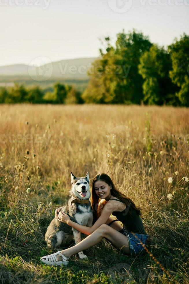 Woman sitting in field with dachshund dog smiling while spending time in nature with friend dog in autumn at sunset while traveling photo