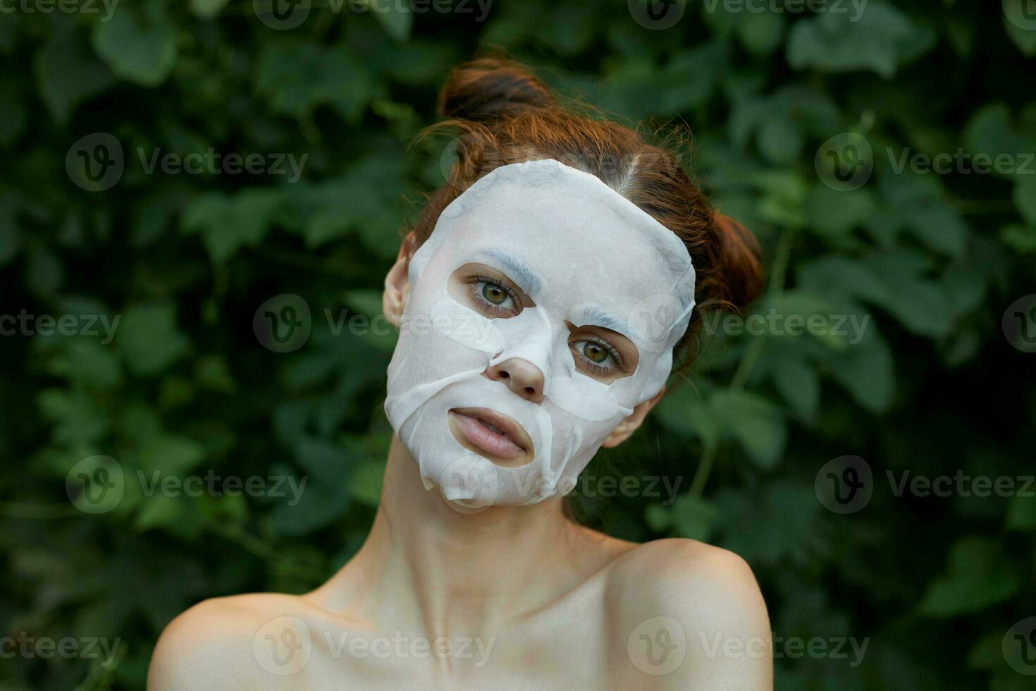 Portrait of a girl cosmetic mask look ahead and bushes in the park cosmetology photo